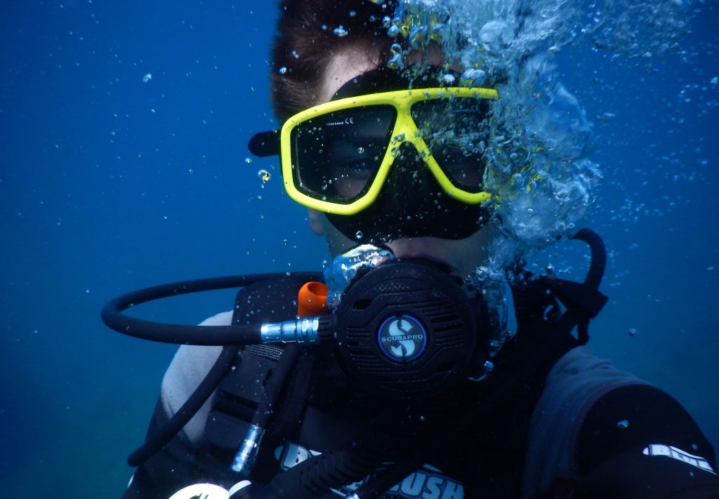 Diver with a yellow mask in blue water